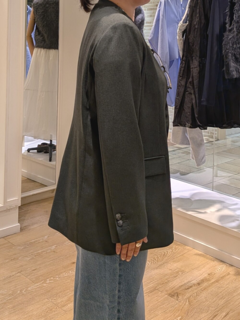 グレー系のノーカラージャケット、ブルー系のデニムパンツ、ブラック系のショルダーバッグを着用したレディースの秋コーディネートの7枚目の写真