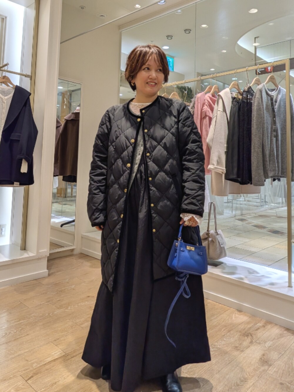 ブラック系のダウンジャケット/コート、ブラック系のワンピース、ホワイト系のシャツ/ブラウスを着用したレディースの秋コーディネートの2枚目の写真