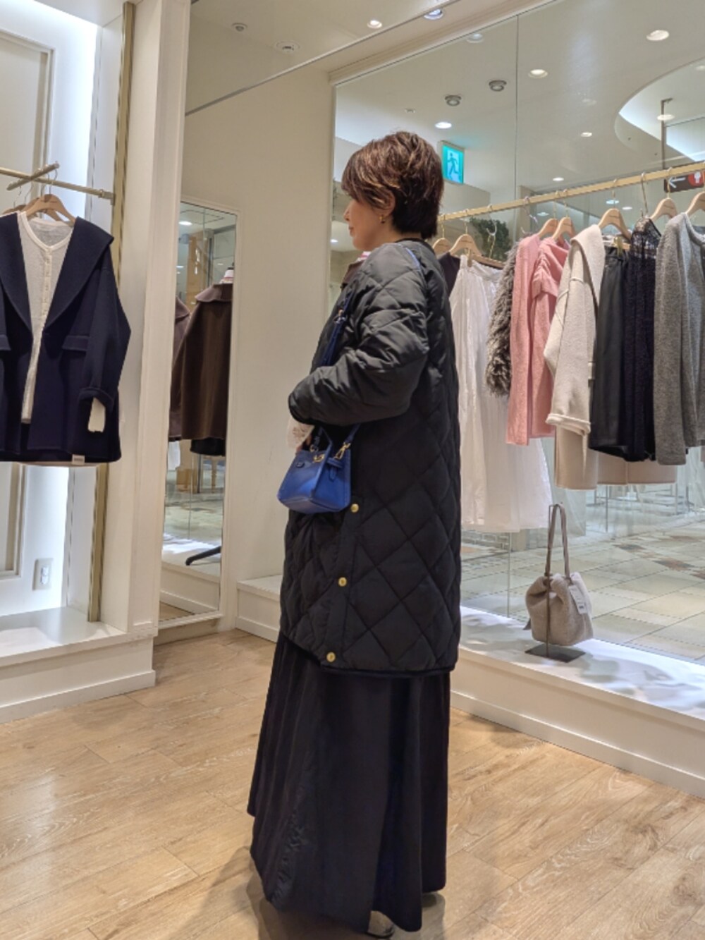 ブラック系のダウンジャケット/コート、ブラック系のワンピース、ホワイト系のシャツ/ブラウスを着用したレディースの秋コーディネートの4枚目の写真