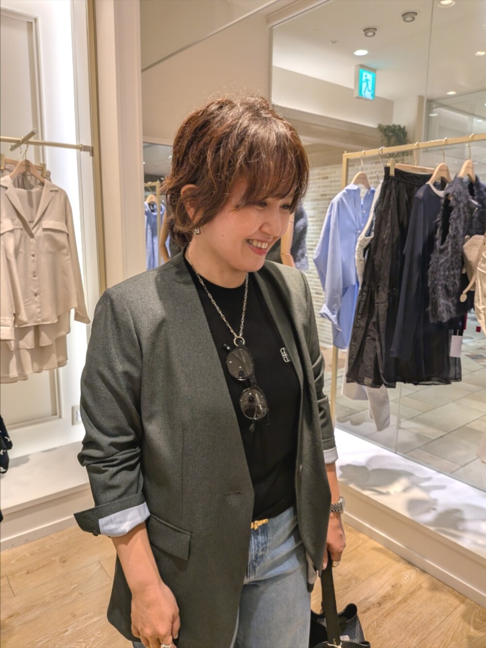 グレー系のノーカラージャケット、ブルー系のデニムパンツ、ブラック系のショルダーバッグを着用したレディースの秋コーディネートの5枚目の写真