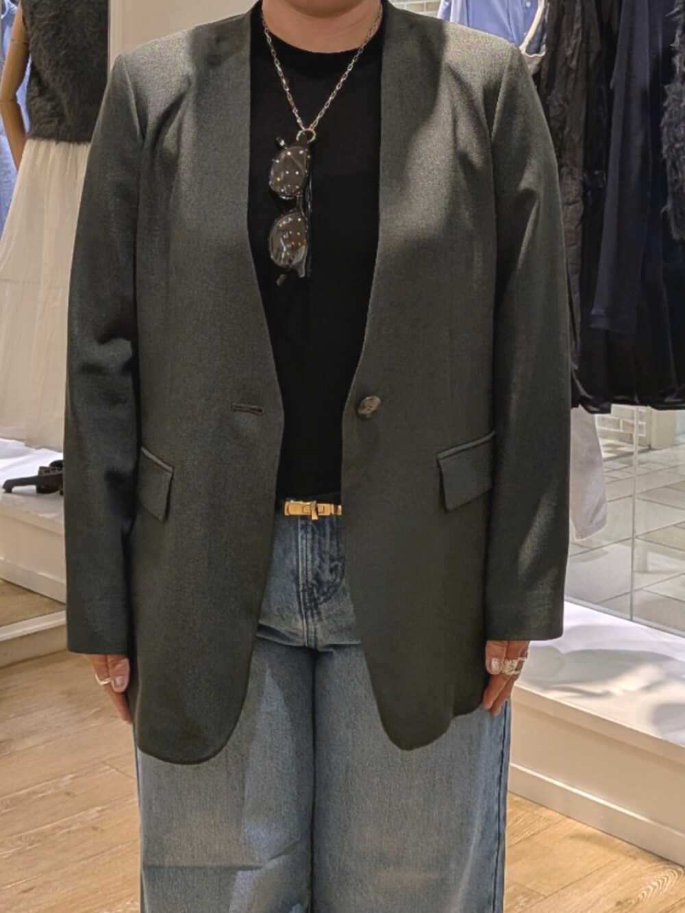 グレー系のノーカラージャケット、ブルー系のデニムパンツ、ブラック系のショルダーバッグを着用したレディースの秋コーディネートの6枚目の写真