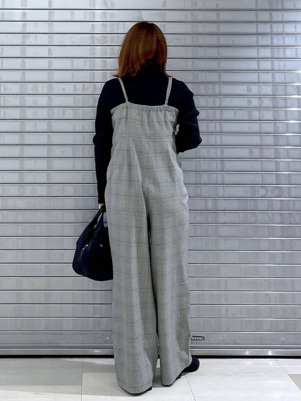 ブラック系のサロペット/オーバーオール、ブラック系のハンドバッグ、グレー系のブーツを着用したレディースの秋コーディネートの4枚目の写真