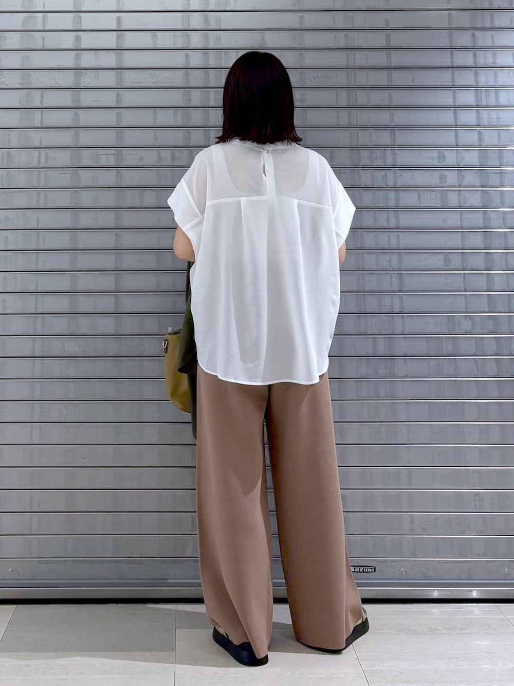 ゴールド系のサンダル、ベージュ系のハンドバッグ、ブラウン系のその他パンツを着用したレディースの秋コーディネートの3枚目の写真