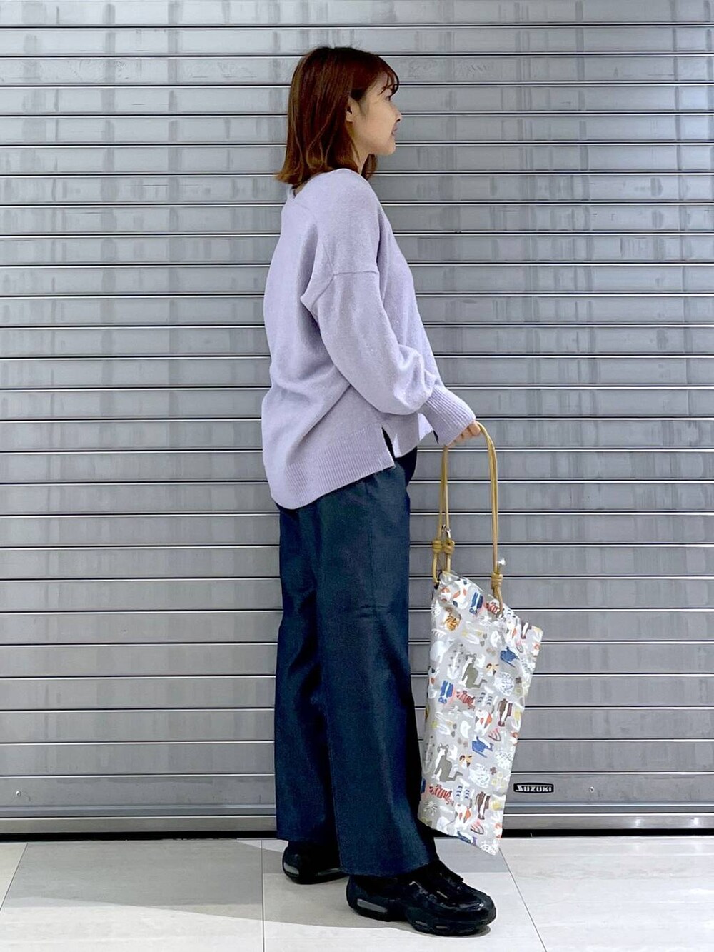 パープル系のニット/セーター、ベージュ系のトートバッグ、ブルー系のデニムパンツを着用したレディースの秋コーディネートの6枚目の写真