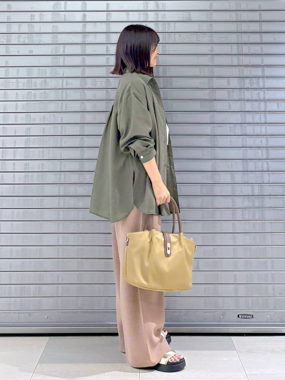 ゴールド系のサンダル、ベージュ系のハンドバッグ、ブラウン系のその他パンツを着用したレディースの秋コーディネートの5枚目の写真