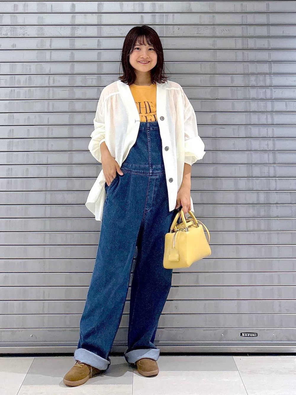 ブルー系のサロペット/オーバーオール、オレンジ系のTシャツ/カットソー、ホワイト系のカーディガン/ボレロを着用したレディースの秋コーディネートの7枚目の写真