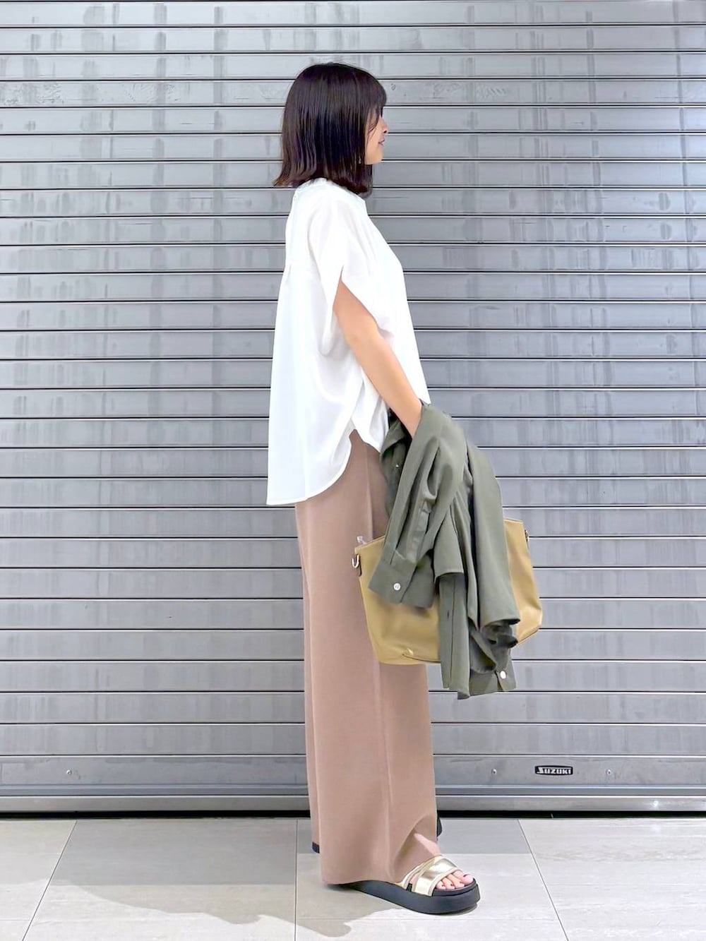 ゴールド系のサンダル、ベージュ系のハンドバッグ、ブラウン系のその他パンツを着用したレディースの秋コーディネートの2枚目の写真