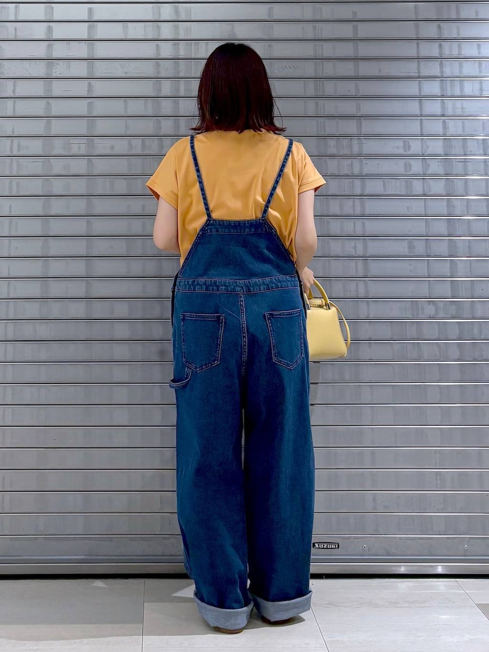 ブルー系のサロペット/オーバーオール、オレンジ系のTシャツ/カットソー、ホワイト系のカーディガン/ボレロを着用したレディースの秋コーディネートの3枚目の写真