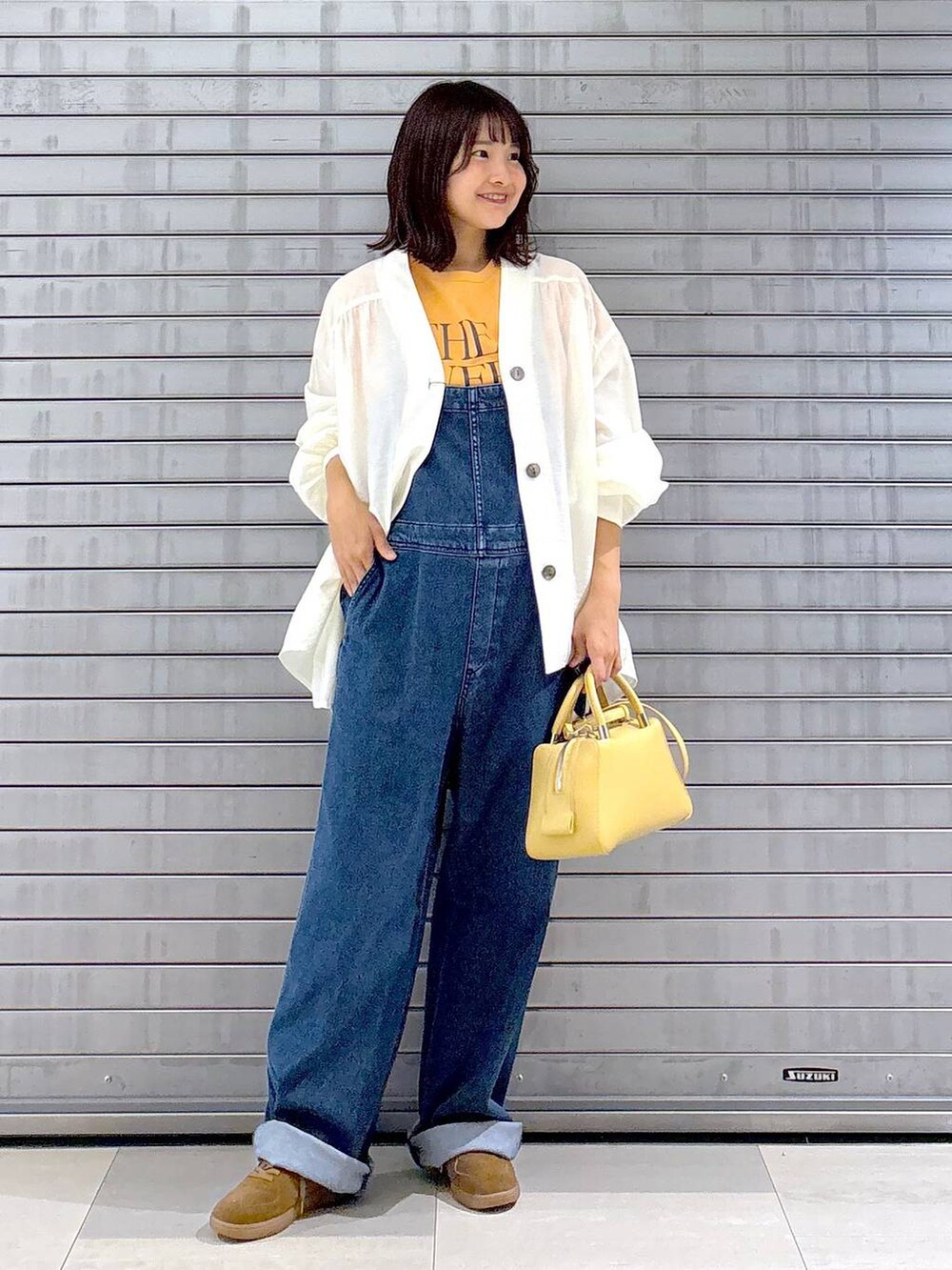 ブルー系のサロペット/オーバーオール、オレンジ系のTシャツ/カットソー、ホワイト系のカーディガン/ボレロを着用したレディースの秋コーディネートの4枚目の写真