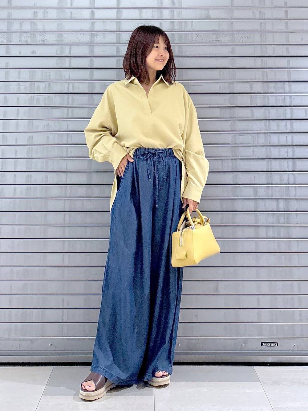 ブラウン系のサンダル、イエロー系のシャツ/ブラウス、ブルー系のデニムパンツを着用したレディースの秋コーディネートの2枚目の写真