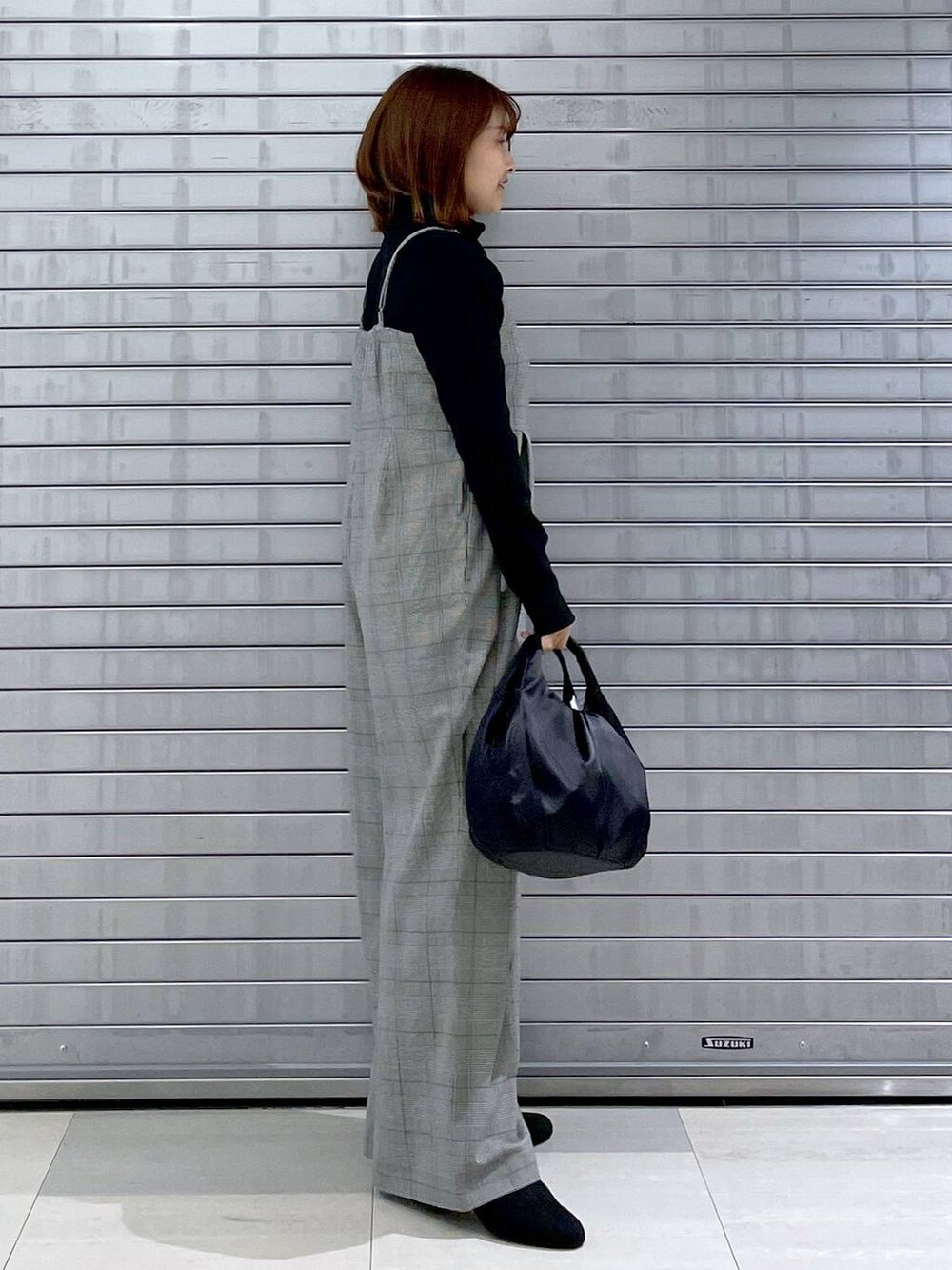 ブラック系のサロペット/オーバーオール、ブラック系のハンドバッグ、グレー系のブーツを着用したレディースの秋コーディネートの3枚目の写真