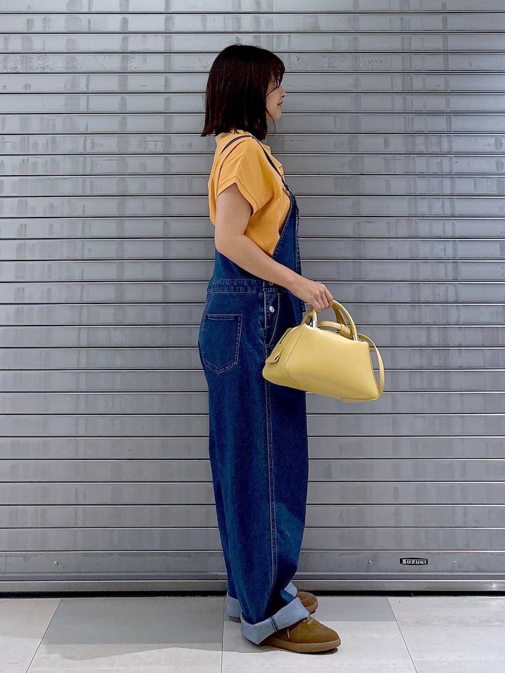 ブルー系のサロペット/オーバーオール、オレンジ系のTシャツ/カットソー、ホワイト系のカーディガン/ボレロを着用したレディースの秋コーディネートの2枚目の写真