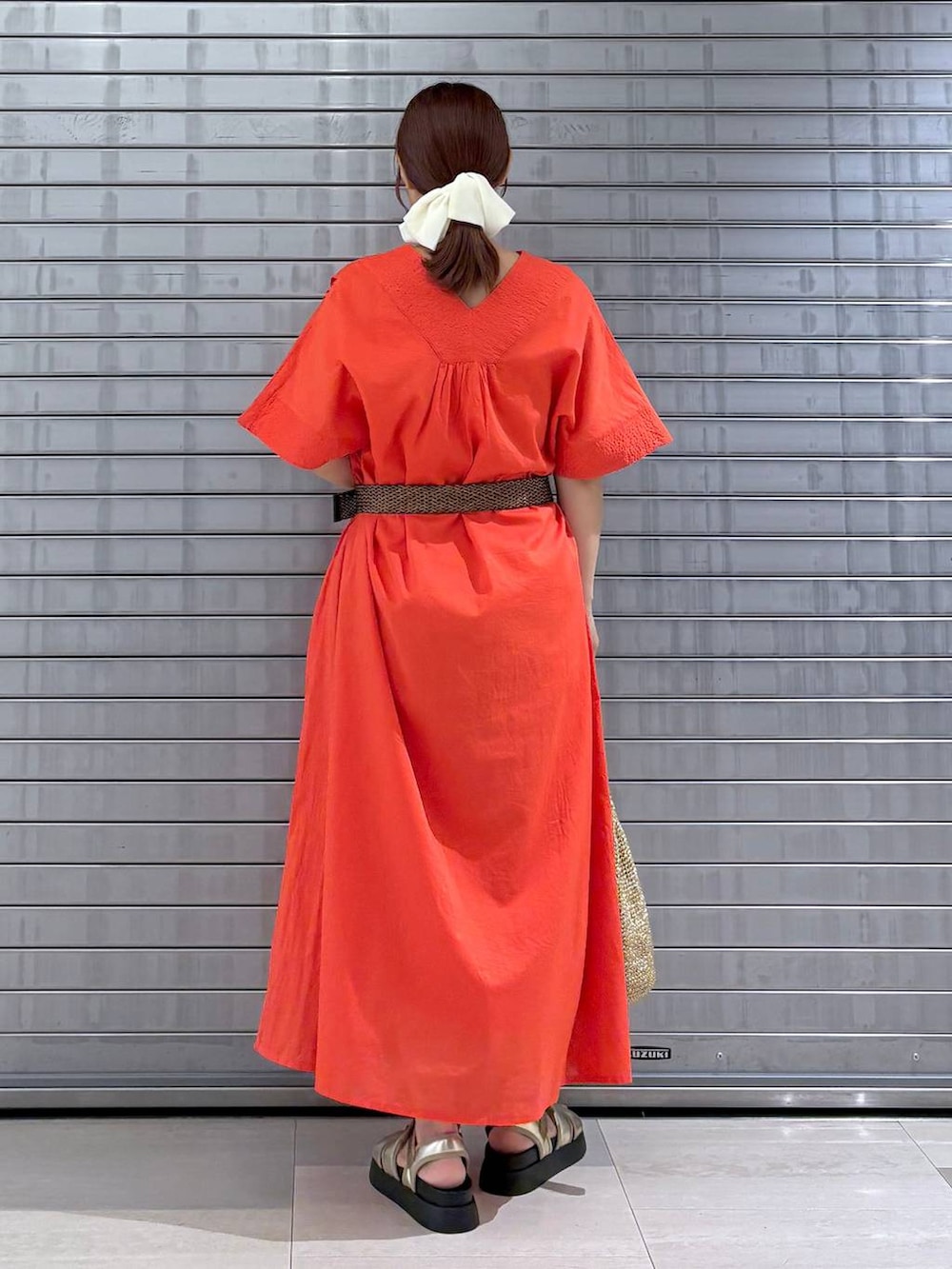 オレンジ系のワンピース、ゴールド系のサンダル、ゴールド系のトートバッグを着用したレディースの夏コーディネートの4枚目の写真