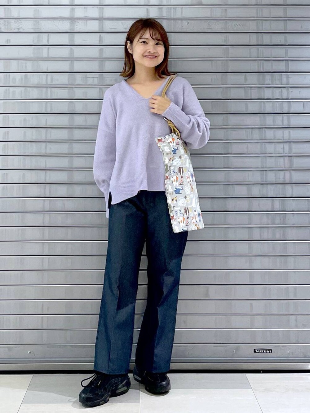 パープル系のニット/セーター、ベージュ系のトートバッグ、ブルー系のデニムパンツを着用したレディースの秋コーディネートの5枚目の写真