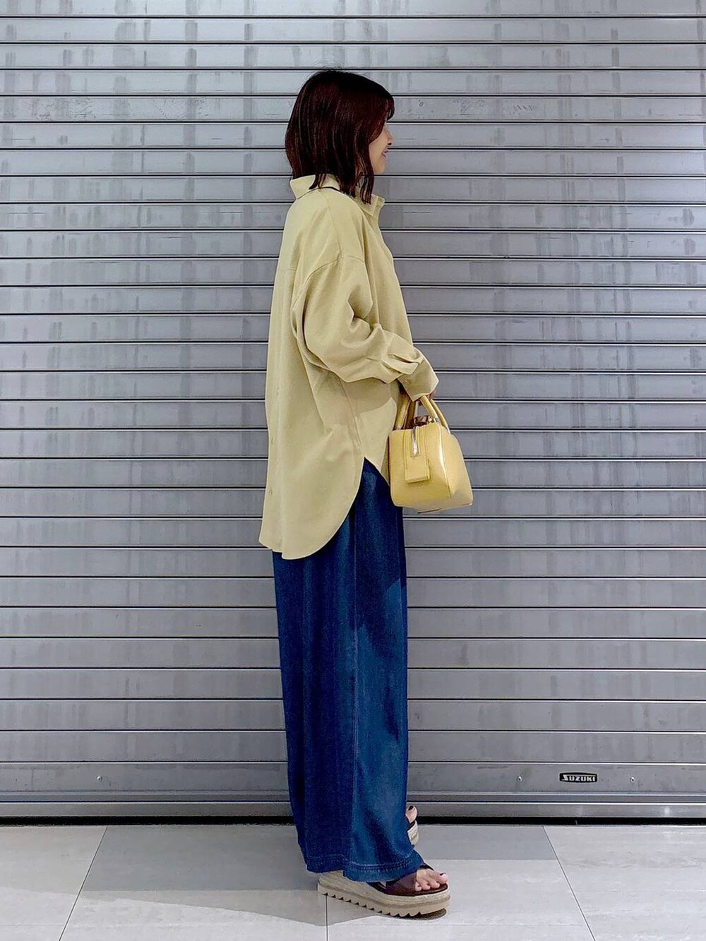 ブラウン系のサンダル、イエロー系のシャツ/ブラウス、ブルー系のデニムパンツを着用したレディースの秋コーディネートの4枚目の写真