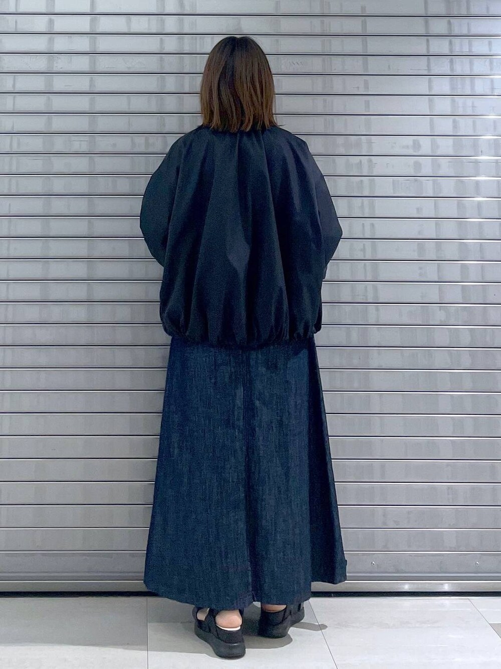 ブラック系のボディバッグ/ウエストポーチ、ブラック系のサンダル、ブルー系のスカートを着用したレディースの春コーディネートの2枚目の写真