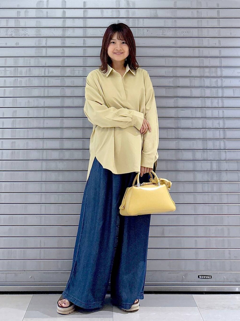 ブラウン系のサンダル、イエロー系のシャツ/ブラウス、ブルー系のデニムパンツを着用したレディースの秋コーディネートの3枚目の写真