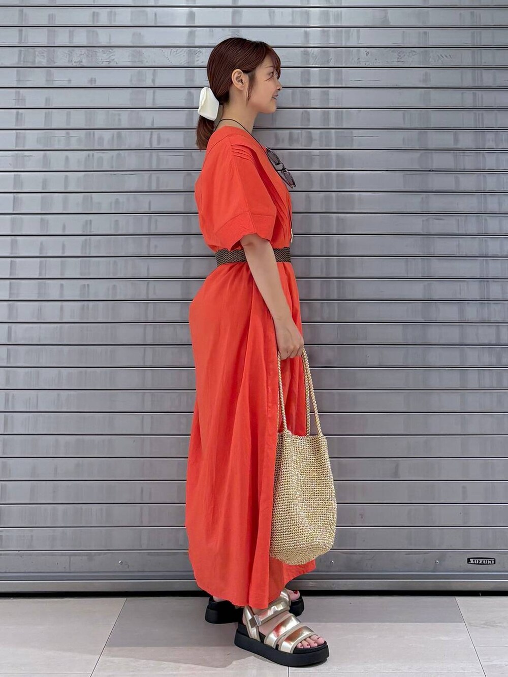 オレンジ系のワンピース、ゴールド系のサンダル、ゴールド系のトートバッグを着用したレディースの夏コーディネートの3枚目の写真