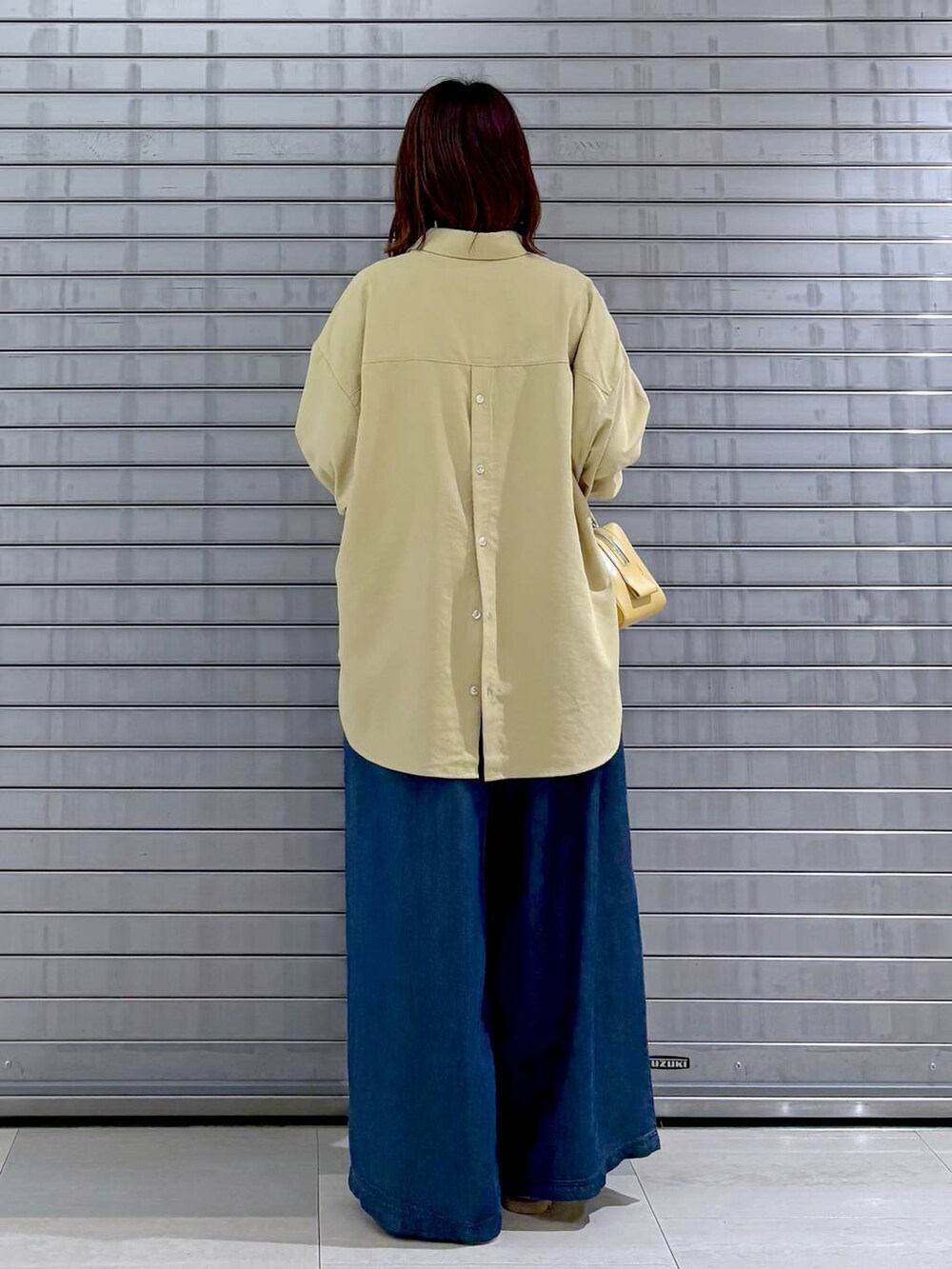 ブラウン系のサンダル、イエロー系のシャツ/ブラウス、ブルー系のデニムパンツを着用したレディースの秋コーディネートの5枚目の写真