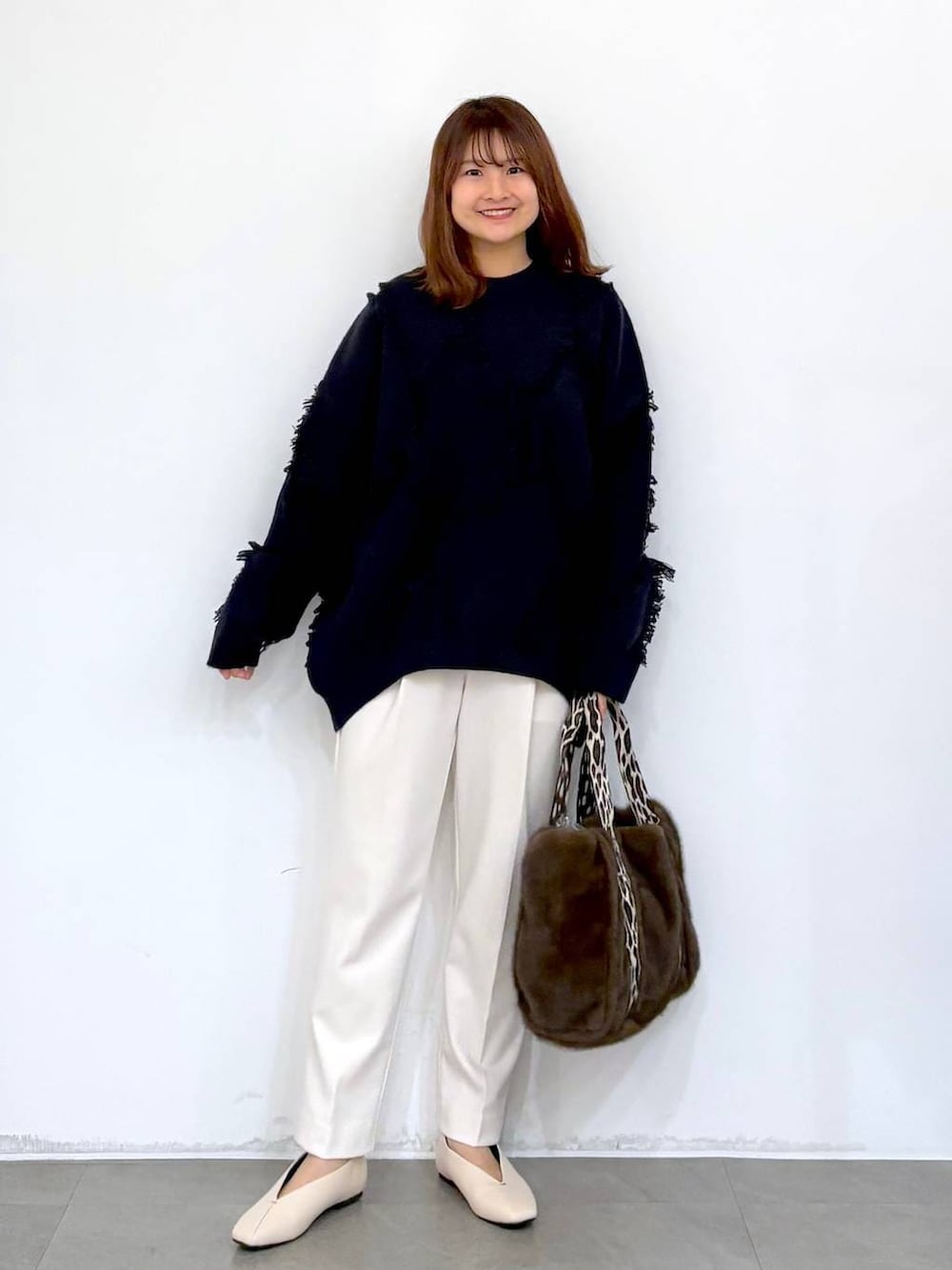 ホワイト系のその他パンツ、ホワイト系のパンプス、ブラウン系のトートバッグを着用したレディースの秋コーディネートの2枚目の写真