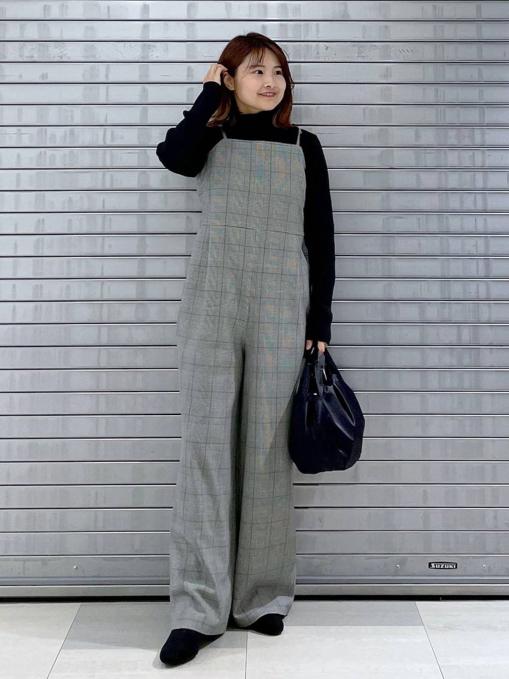 ブラック系のサロペット/オーバーオール、ブラック系のハンドバッグ、グレー系のブーツを着用したレディースの秋コーディネートの2枚目の写真