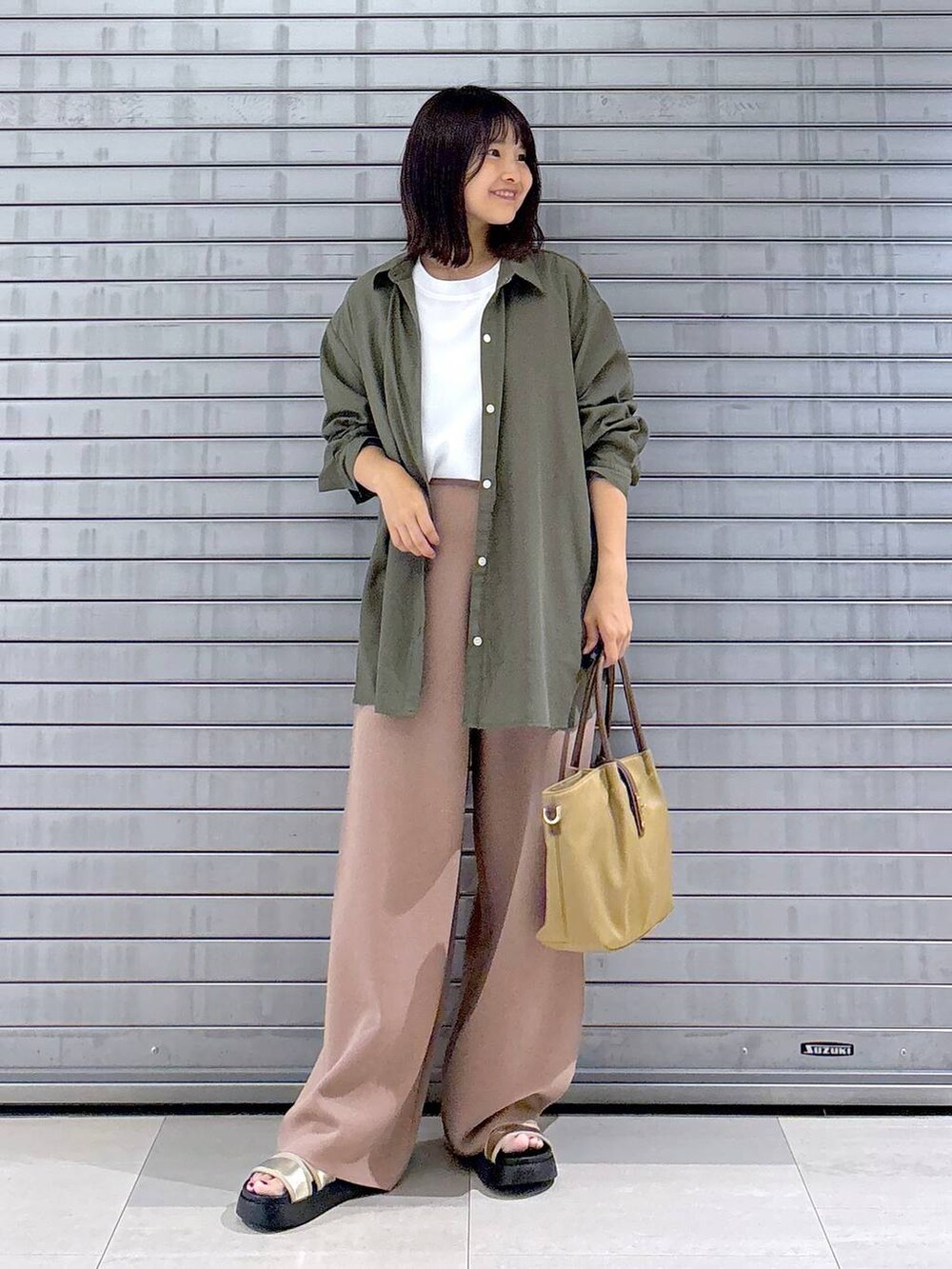 ゴールド系のサンダル、ベージュ系のハンドバッグ、ブラウン系のその他パンツを着用したレディースの秋コーディネートの4枚目の写真