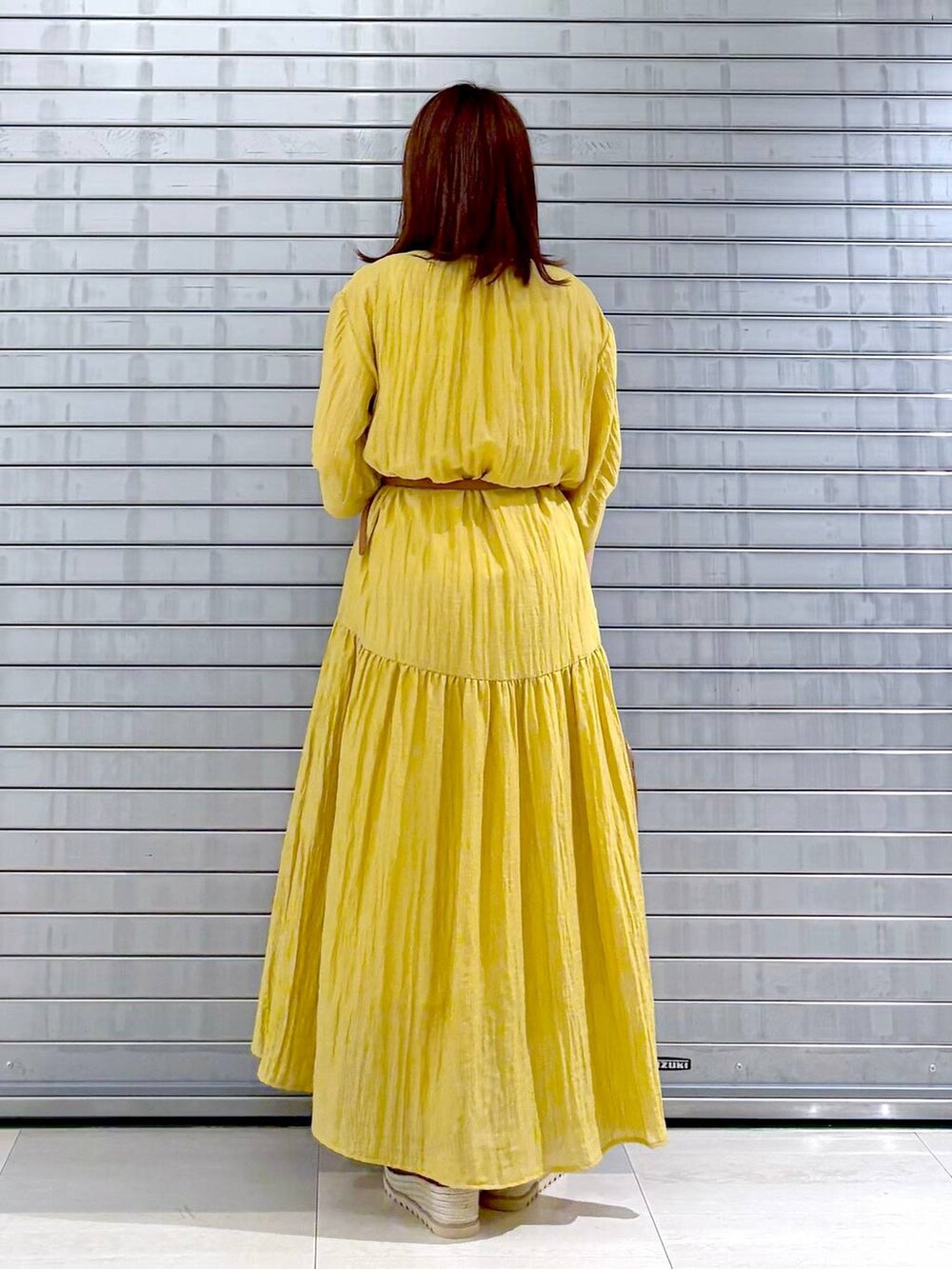 ブラウン系のハンドバッグ、イエロー系のワンピース、ブラウン系のベルトを着用したレディースの夏コーディネートの4枚目の写真