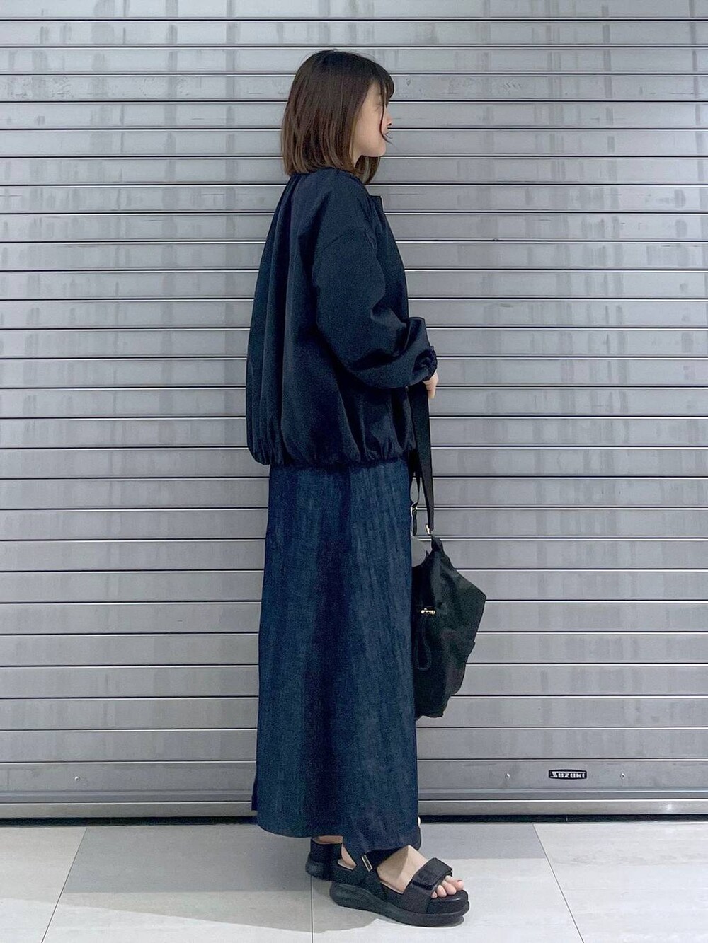 ブラック系のボディバッグ/ウエストポーチ、ブラック系のサンダル、ブルー系のスカートを着用したレディースの春コーディネートの3枚目の写真