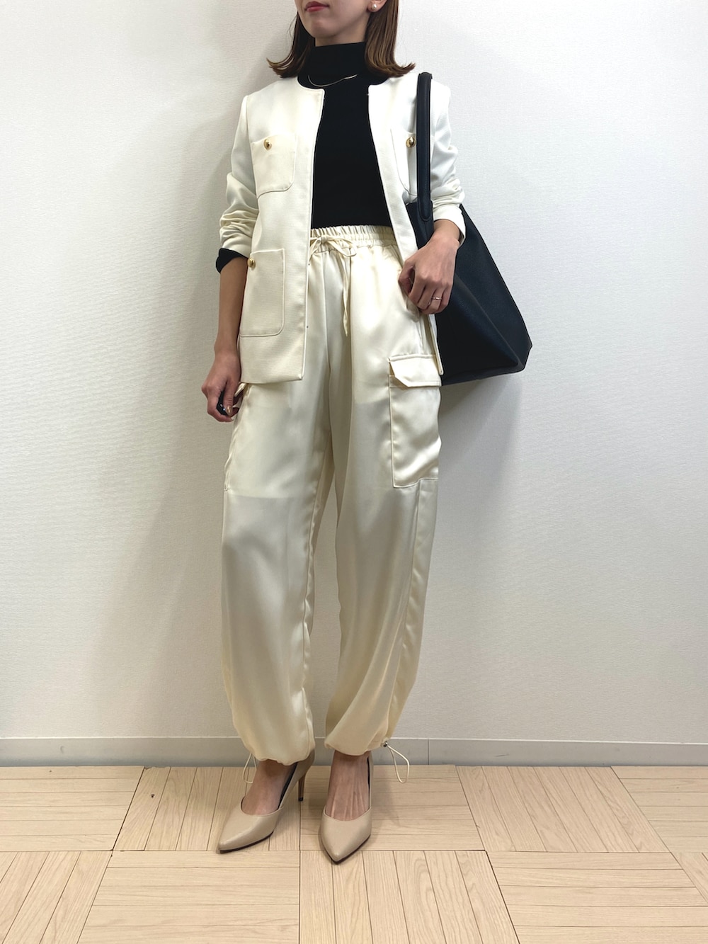 ブラック系のニット/セーター、ホワイト系のノーカラージャケット、ホワイト系のカーゴパンツを着用したレディースの冬コーディネートの2枚目の写真