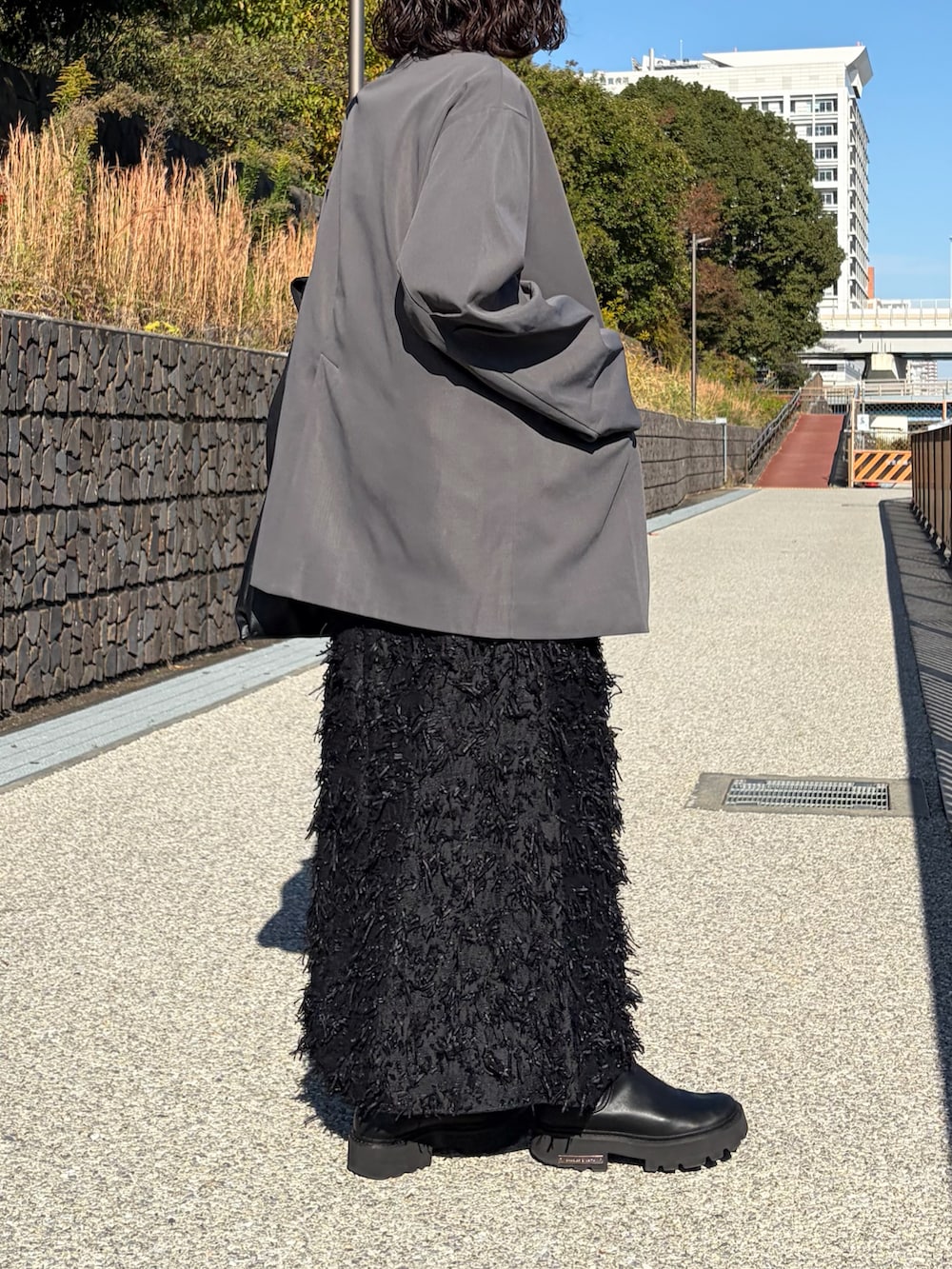 ブラック系のスカート、ブラック系のキャミソール、ブラック系のブーツを着用したレディースの春コーディネートの3枚目の写真