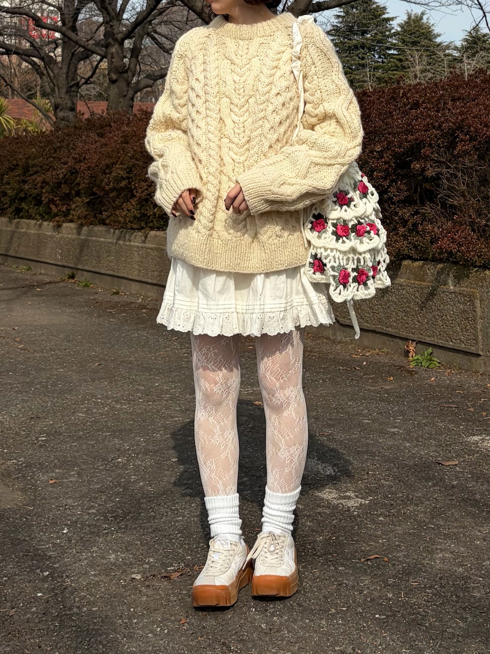 ホワイト系のショルダーバッグ、ホワイト系のニット/セーター、ホワイト系のスカートを着用したレディースの春コーディネートの2枚目の写真