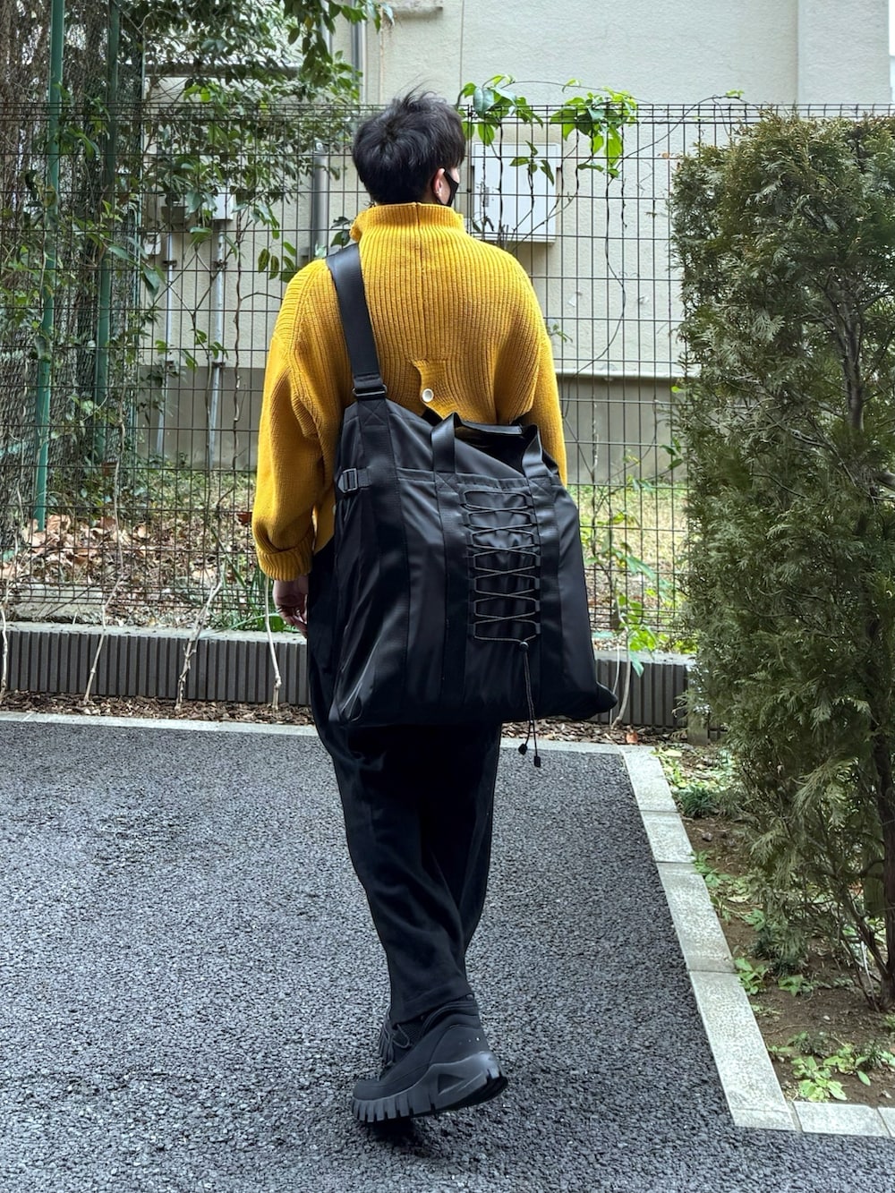 ブラック系のハンドバッグ、イエロー系のカーディガン/ボレロ、ブラック系のスラックスを着用したメンズの冬コーディネートの2枚目の写真