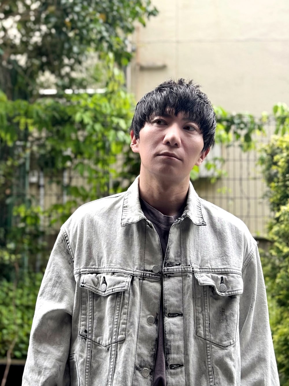 ホワイト系のデニムジャケット、グレー系のTシャツ/カットソー、ブラック系のハンドバッグを着用したメンズの春コーディネートの2枚目の写真