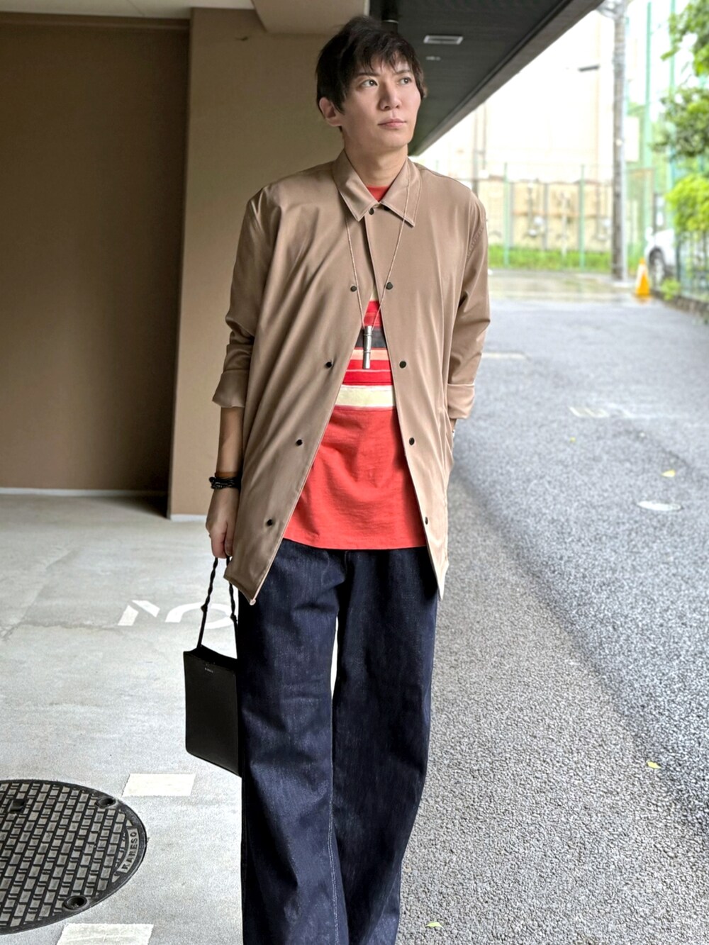 ベージュ系のトップス、レッド系のTシャツ/カットソー、ブラック系のショルダーバッグを着用したメンズの春コーディネートの3枚目の写真