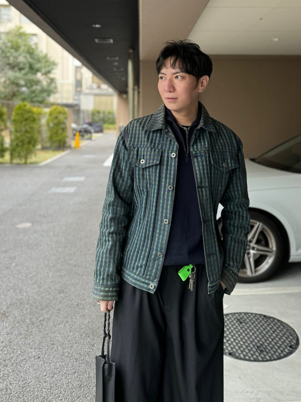 パープル系のトップス、グリーン系のデニムジャケット、ブラック系のショルダーバッグを着用したメンズの春コーディネートの2枚目の写真