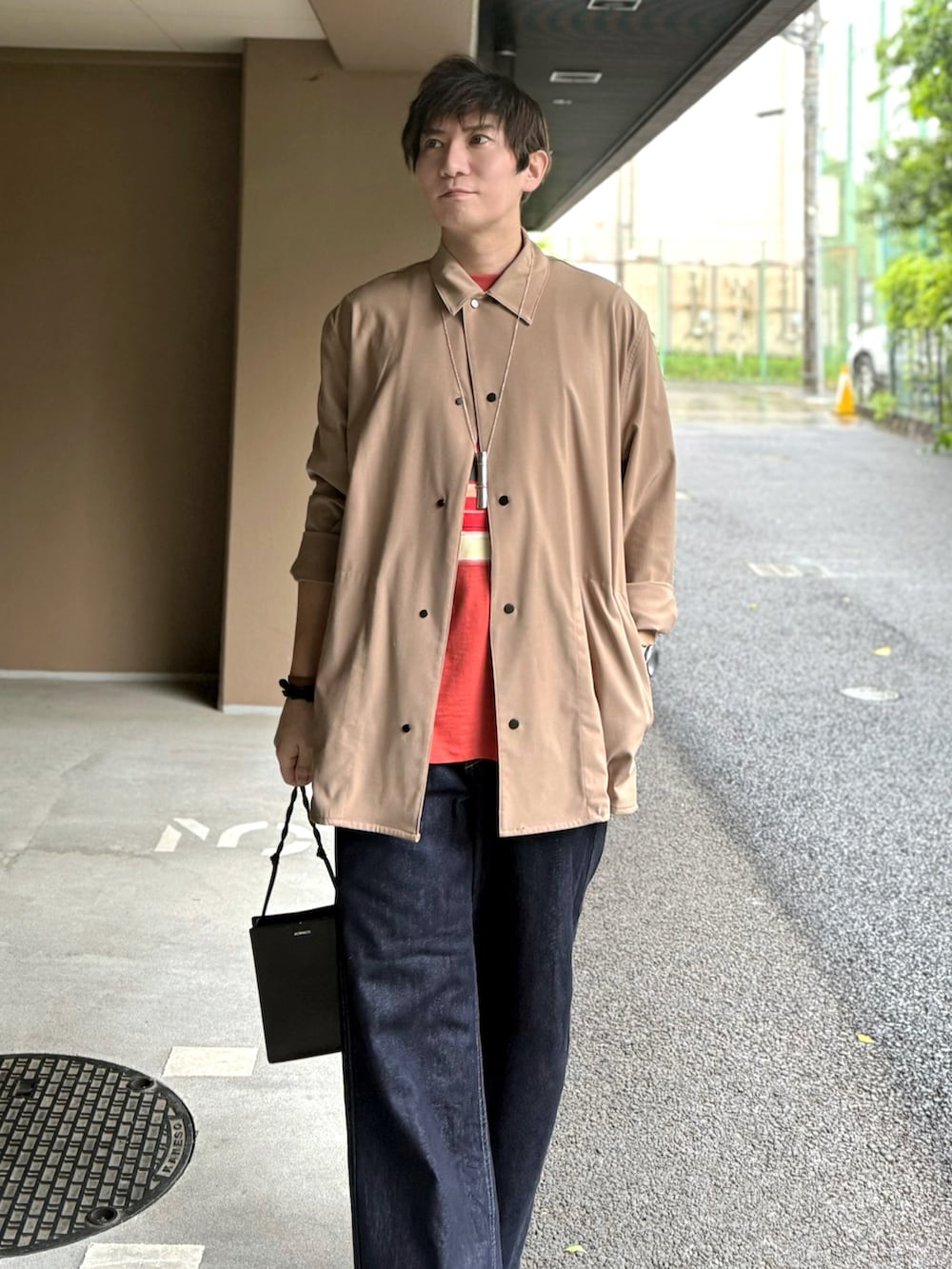 ベージュ系のトップス、レッド系のTシャツ/カットソー、ブラック系のショルダーバッグを着用したメンズの春コーディネートの2枚目の写真