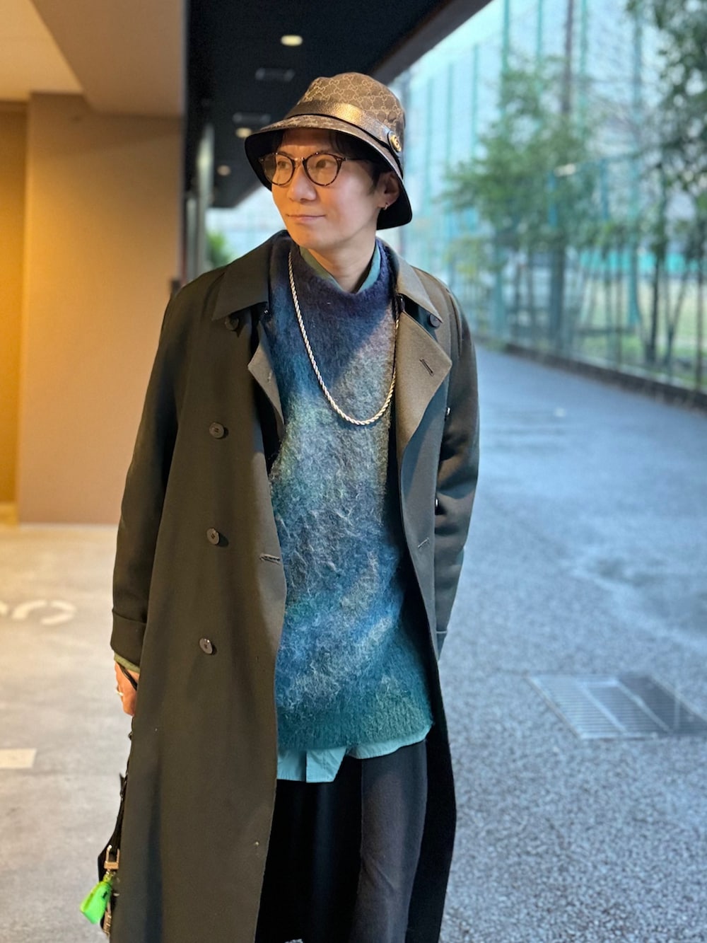 グリーン系のシャツ/ブラウス、グリーン系のニット/セーター、グリーン系のトレンチコートを着用したメンズの春コーディネートの4枚目の写真