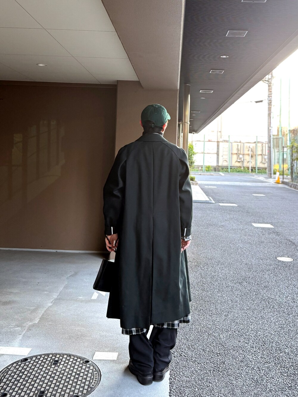 グリーン系のトレンチコート、ブラック系のモッズコート、ブラック系のショルダーバッグを着用したメンズの冬コーディネートの2枚目の写真