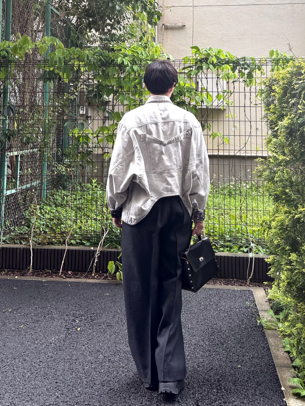 ホワイト系のデニムジャケット、グレー系のTシャツ/カットソー、ブラック系のハンドバッグを着用したメンズの春コーディネートの3枚目の写真