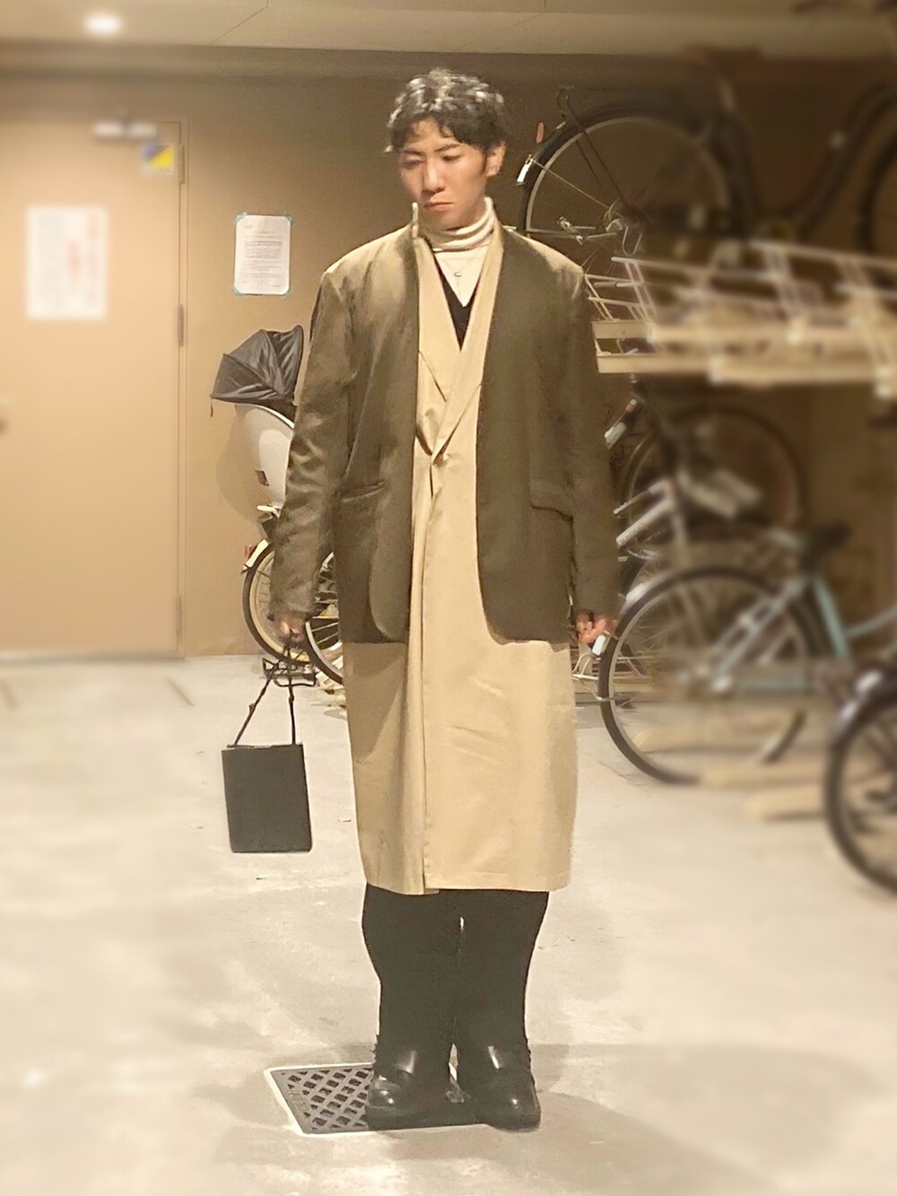 ベージュ系のチェスターコート、ホワイト系のニット/セーター、ブラック系のベストを着用したメンズの冬コーディネートの2枚目の写真