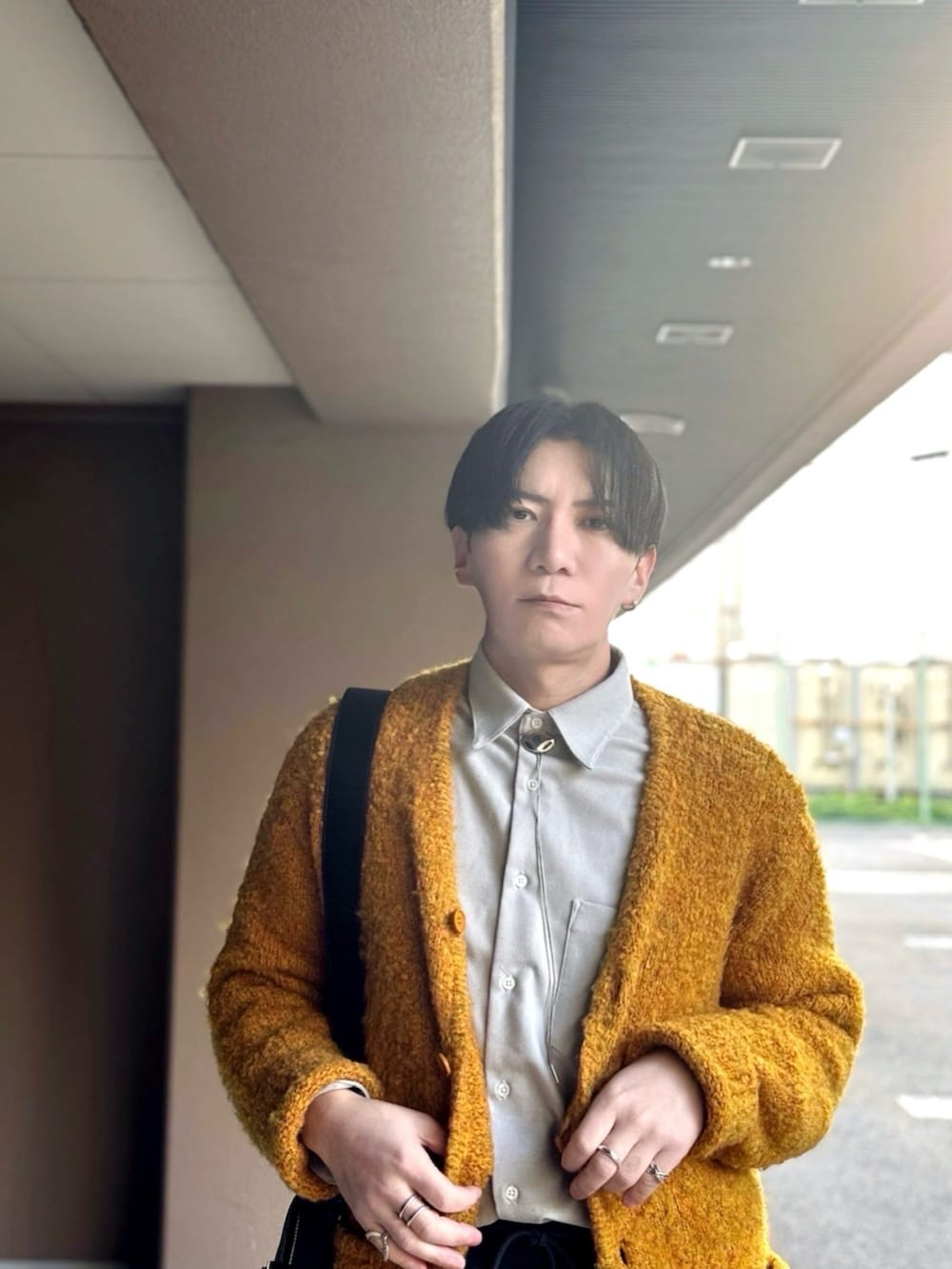 イエロー系のカーディガン/ボレロ、グレー系のシャツ/ブラウス、ブラック系のショルダーバッグを着用したメンズの冬コーディネートの3枚目の写真