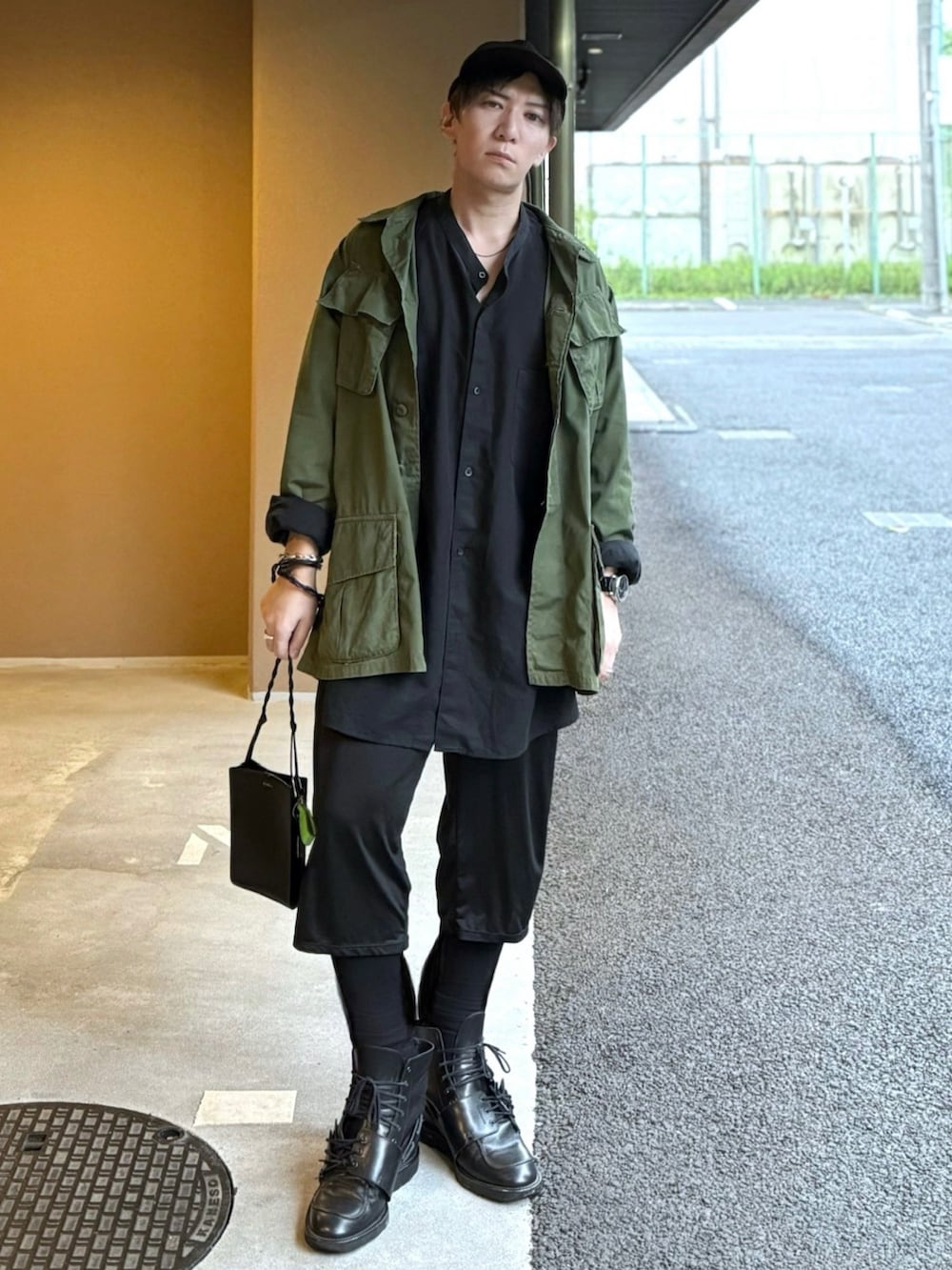 ブラック系のシャツ/ブラウス、グリーン系のミリタリージャケット、ブラック系のショルダーバッグを着用したメンズの春コーディネートの3枚目の写真