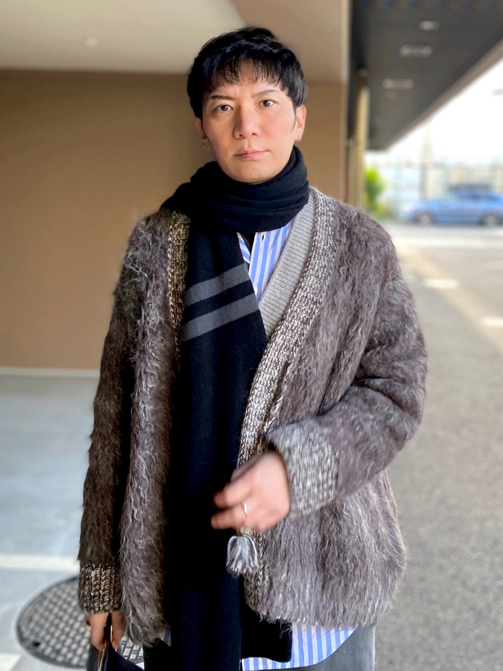 グレー系のカーディガン/ボレロ、グレー系のデニムパンツ、ブラック系のトートバッグを着用したメンズの冬コーディネートの3枚目の写真