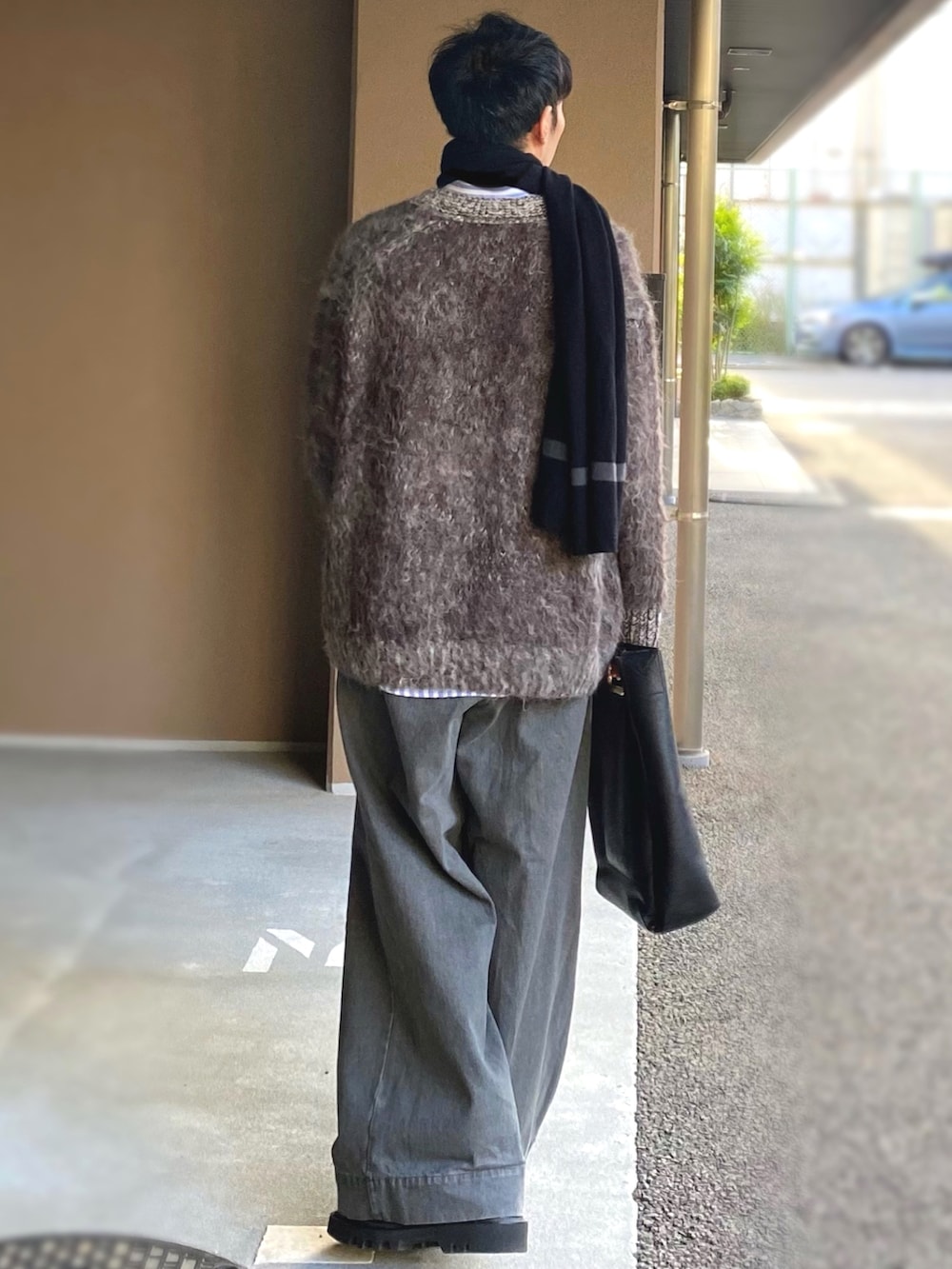 グレー系のカーディガン/ボレロ、グレー系のデニムパンツ、ブラック系のトートバッグを着用したメンズの冬コーディネートの2枚目の写真