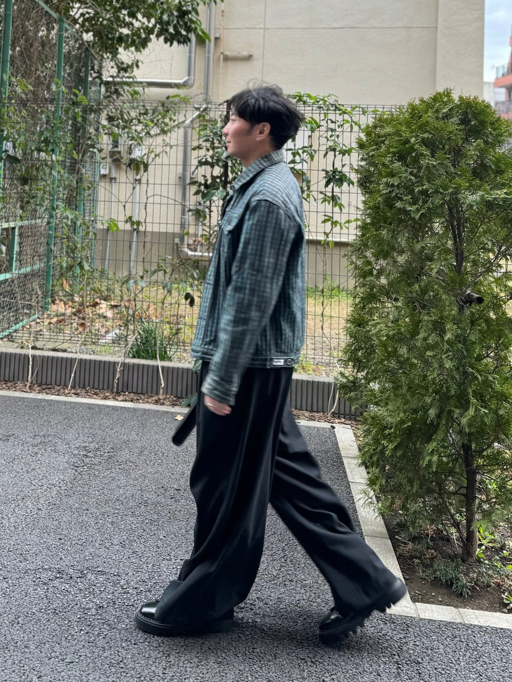 パープル系のトップス、グリーン系のデニムジャケット、ブラック系のショルダーバッグを着用したメンズの春コーディネートの3枚目の写真