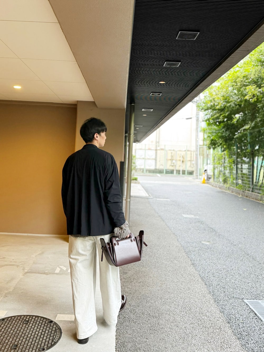 グレー系のニット/セーター、ブラック系のテーラードジャケット、ブラウン系のショルダーバッグを着用したメンズの秋コーディネートの2枚目の写真