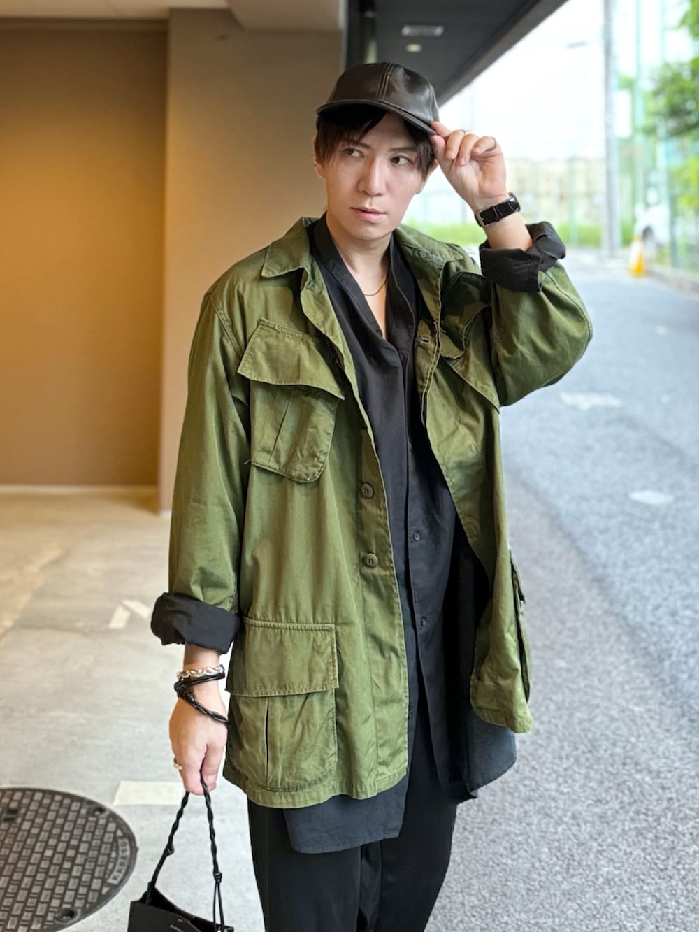 ブラック系のシャツ/ブラウス、グリーン系のミリタリージャケット、ブラック系のショルダーバッグを着用したメンズの春コーディネートの2枚目の写真