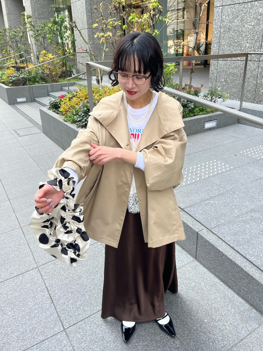 ホワイト系のキャミソール、ベージュ系のトレンチコート、ホワイト系のTシャツ/カットソーを着用したレディースの冬コーディネートの5枚目の写真