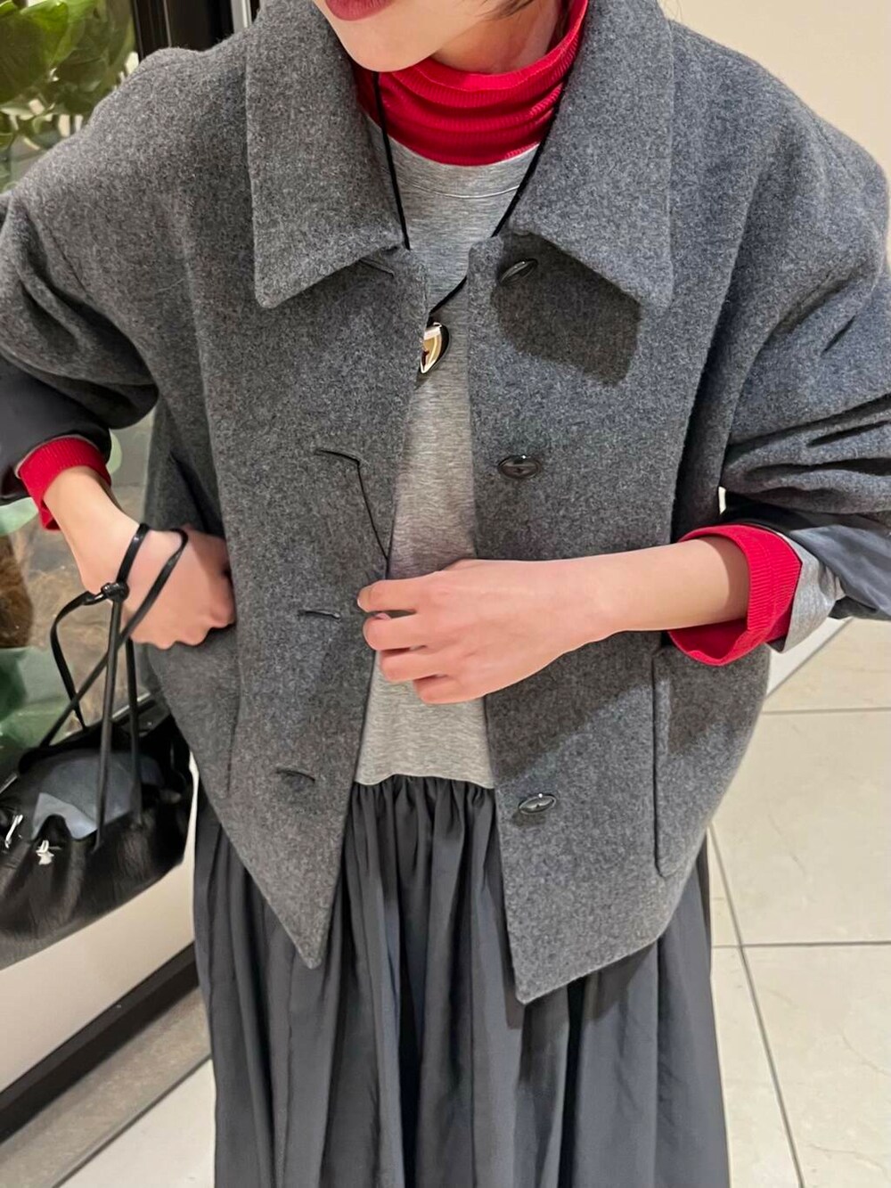 ブラック系のショルダーバッグ、レッド系のTシャツ/カットソー、ブラック系のブーツを着用したレディースの秋コーディネートの6枚目の写真