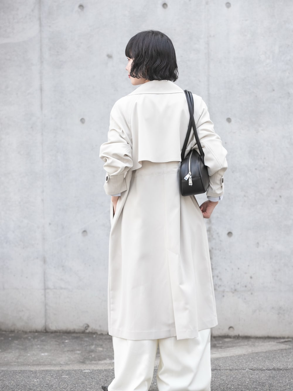 グレー系のトレンチコート、グレー系のニット/セーター、ブルー系のシャツ/ブラウスを着用したレディースの冬コーディネートの3枚目の写真